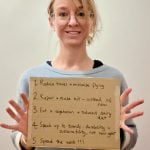 Emma Pooley holds up a cardboard sign with her Green Runner pledges.