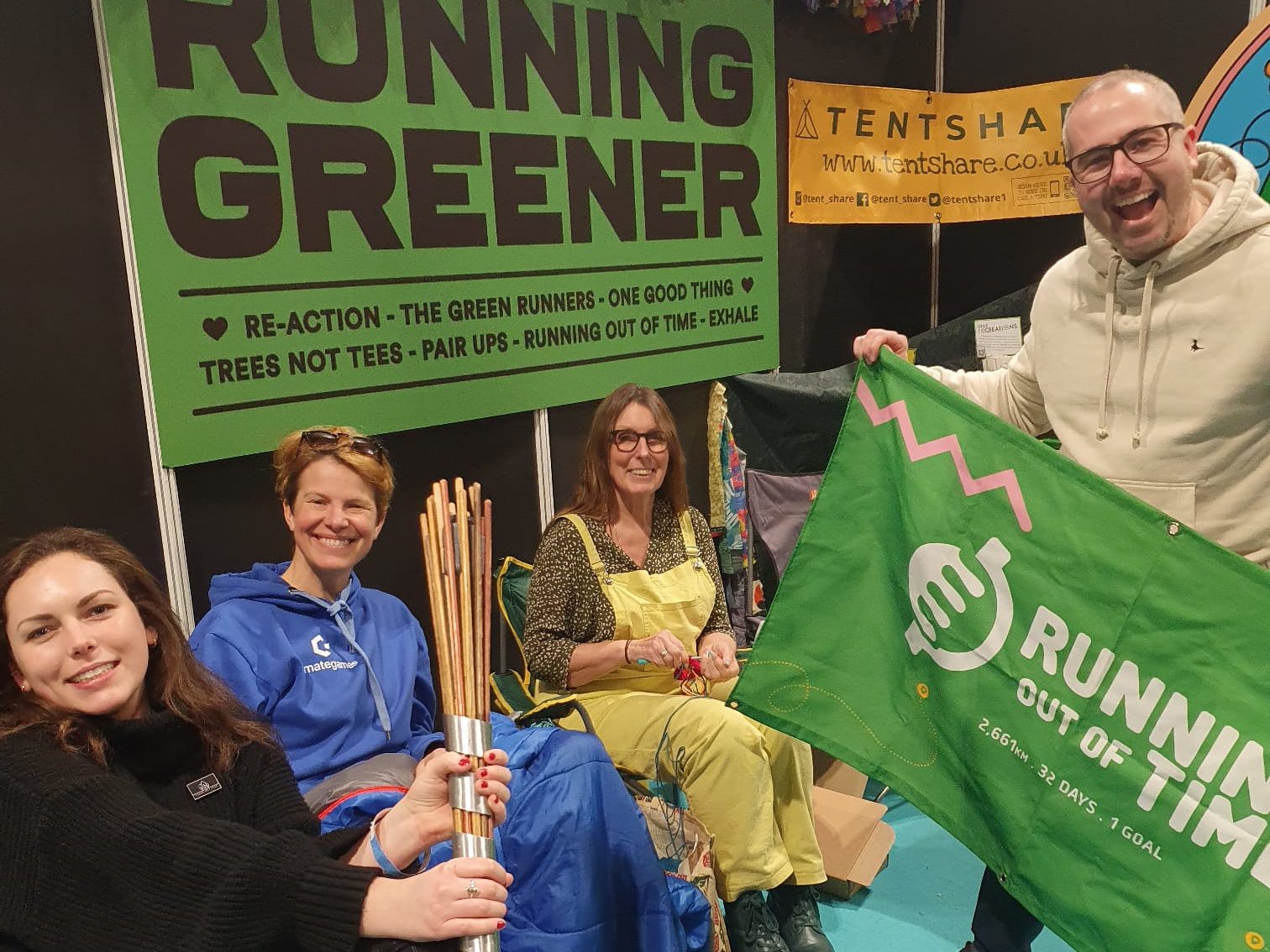 A group of people sitting beneath a banner reading Running Greener - they are taking part in a panel discussion