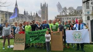 A group of green runners in front of Big Ben in London campaigning for greater action of the climate emergency. They are holding banners reading 'We can't run away from this'