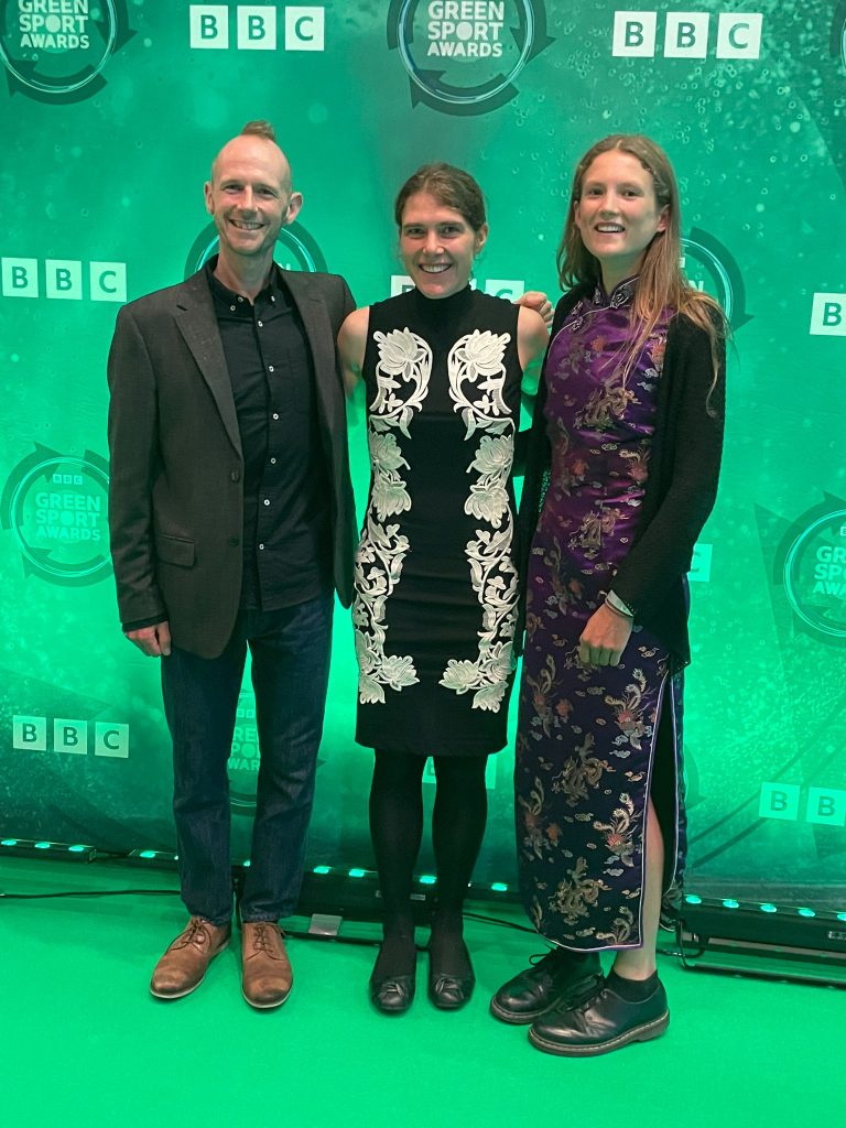 Damian Hall, left, Jasmin Paris, middle and Innes FitzGerald, right attend the BBC Green Sport awards standing in front of a green background.
