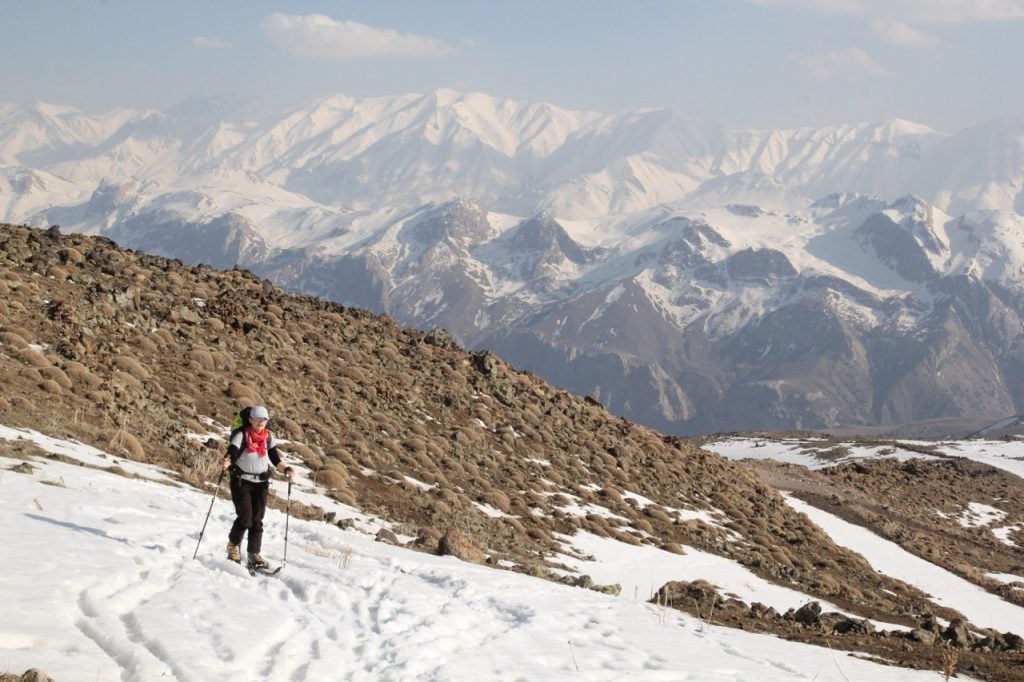 Shirin skiing on a patch of snow in Iran with a background full of snowy mountains