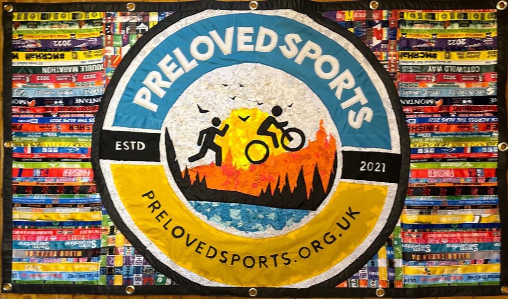 A colourful banner with a circle in the centre which says Preloved Sports, Established 2021 and the website. The banner is half blue, half yellow, with a runner and a cyclist at the centre. The background is a colourful mix of old race medal straps.